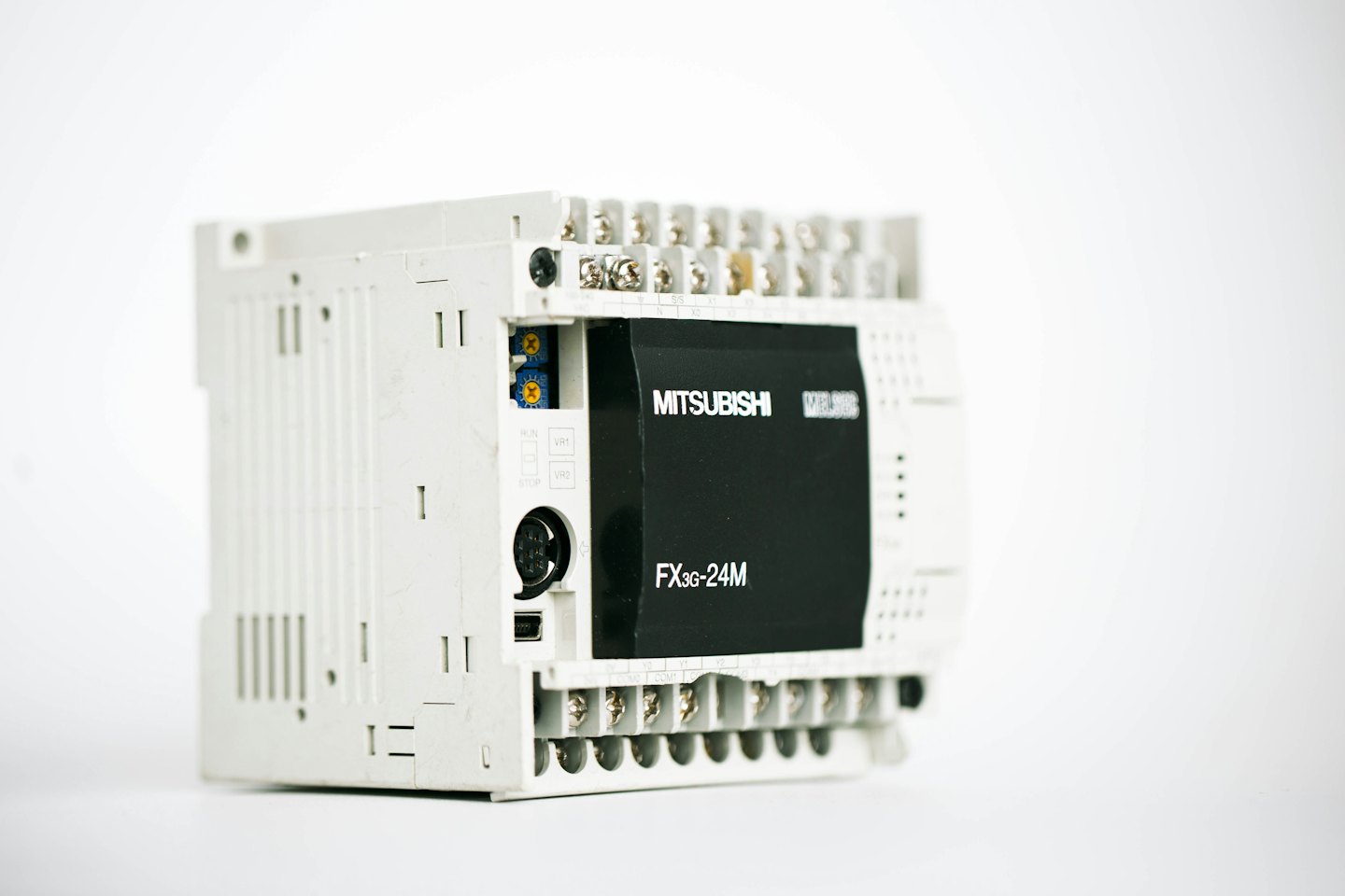 Unidad de controlador lógico programable industrial en blanco y negro con terminales y texto.
